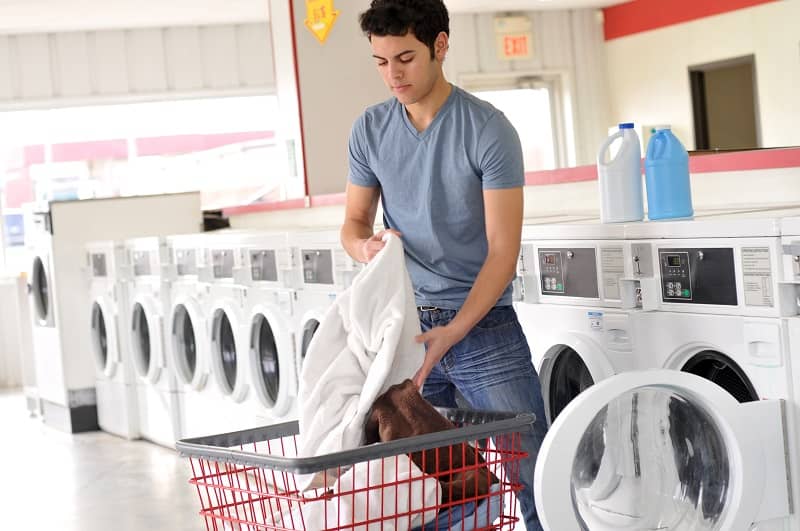 hispanic young man at a laundromat washing his clothes cm 1